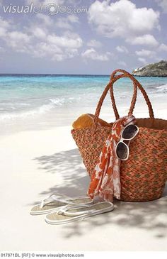 a straw bag sitting on top of a sandy beach next to the ocean and an island