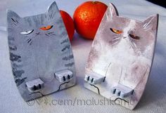 two paper mache cats sitting next to an orange