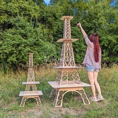 a woman standing in front of the eiffel tower model with her hands up