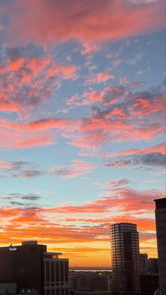 an orange and blue sky with clouds in the foreground is seen from a tall building