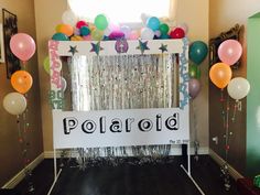 an entrance decorated with balloons and streamers for a polaroid themed birthday party at home