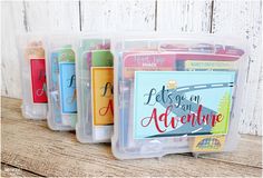 three plastic containers filled with different types of pens and magnets on top of a wooden table