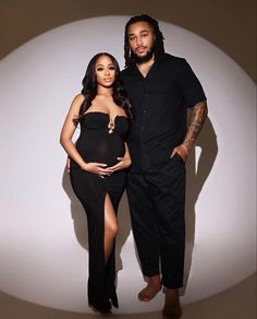 a man and woman standing next to each other in front of a white wall with a shadow on it