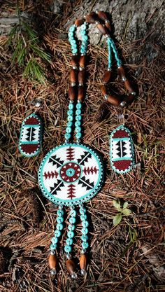 a beaded necklace and earring set on the ground next to a tree trunk