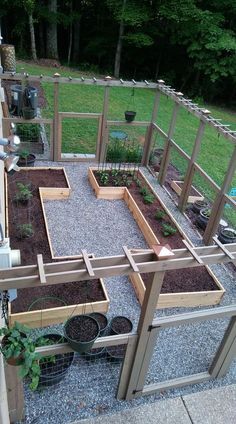 an outdoor garden area with various plants and potted plants in the center, surrounded by wooden fences