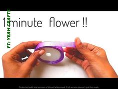 two hands holding a purple object with the words minute flower on it in front of a white background