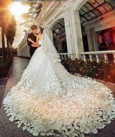 the bride and groom are standing in front of a building with white flowers on it