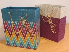 two colorful bags sitting next to each other on top of a wooden table with writing on them