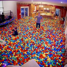 a man standing in a room filled with lots of colorful balls and plastic cups on the floor