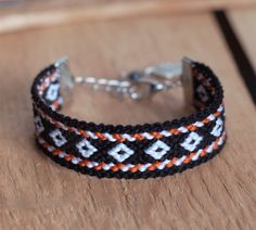 a black and white bracelet with an orange design