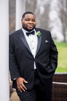 a man in a tuxedo standing next to a pillar