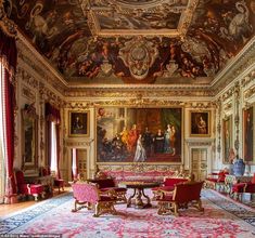 an ornately decorated room with red chairs and paintings on the walls, along with carpeted flooring