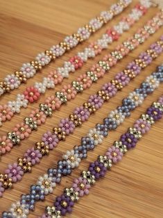 beaded bracelets are lined up on a wooden table with beads in different colors