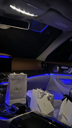 the interior of a car is lit up with blue lights and shopping bags in front of it