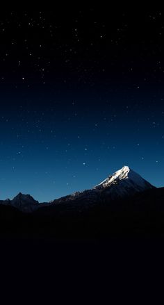 the night sky is lit up with stars above mountains and snow - capped peaks in the foreground