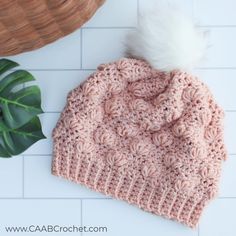 a crocheted beanie with a white pom - pom on top