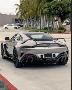 a silver sports car parked in a parking lot next to some palm trees and buildings