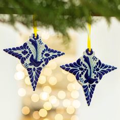 two blue and white ornaments hanging from a christmas tree