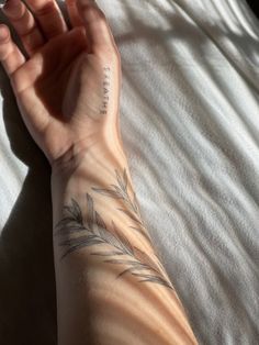 a person's arm with a tattoo on it sitting on top of a bed