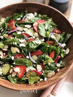 a salad with strawberries, cucumbers and feta cheese in a wooden bowl