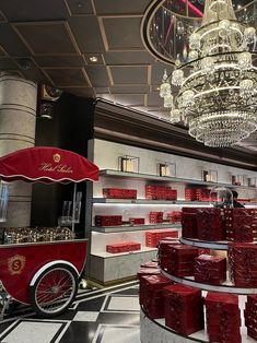 a red cart is in the middle of a room with chandeliers hanging from the ceiling