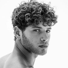 a man with curly hair and no shirt on posing for a black and white photo