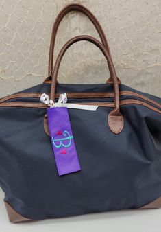 "Personalized purple ribbon luggage tag, embroidered with a monogram or name and little hearts.  Main ribbon tag is approximately 6\" long, tie is approximately 10\" long. Great for travel and spotting your luggage in a sea of sameness! If you would like a different color thread for the name, monogram or hearts, please indicate that in the notes to the seller. Luggage tag is purple, but the tie may change from time to time, depending on my ribbon supply. (colors may appear slightly different due to monitor variations)" Monogrammed Luggage, Luggage Tags Diy, Suitcase Tag, Suitcase Tags, Tags Diy, Custom Luggage, Custom Luggage Tags, Travel Luggage Tag, Purple Ribbon