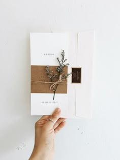 a person holding up a card with a plant on it and the paper is wrapped in twine