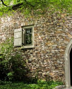 a stone building with an arched window in the middle of it's front yard