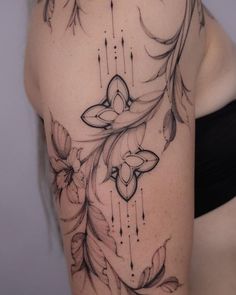 a woman's shoulder with flowers and feathers on her left side, tattoo style