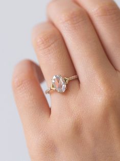 a woman's hand with a diamond ring on top of her finger and the other hand holding an engagement ring