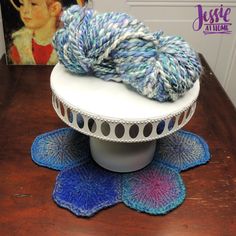 there is a blue and white yarn on top of a table with two crocheted doily