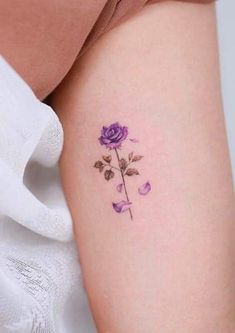 a small purple rose tattoo on the right arm