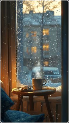 a coffee cup sitting on top of a table next to a window covered in rain