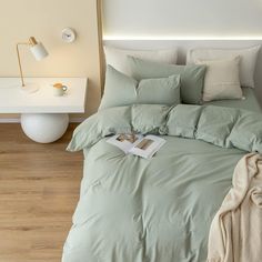 a bed with light green sheets and pillows