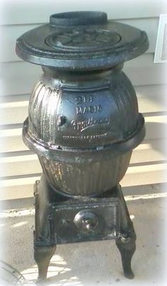 an old fashioned cast iron stove sitting on the side of a house in front of a door