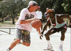 two men are playing basketball while others watch