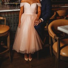 a man and woman sitting next to each other in front of a bar with chairs