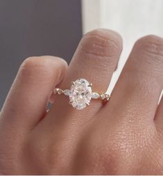 a woman's hand with a diamond ring on top of her finger and the bottom half