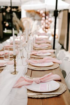 the table is set with pink and white napkins, place settings, and candles