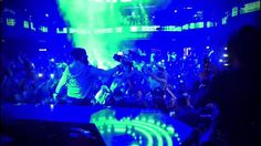 a dj performing in front of a crowd at a concert with green and blue lights