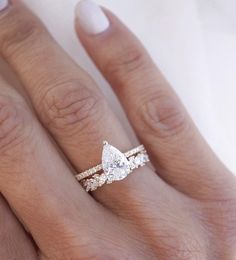 a woman's hand with a wedding ring on it and an engagement band in the middle