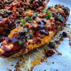 an enchilada with black olives, tomatoes and green onions on it