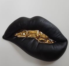 a close up of a black and gold lip