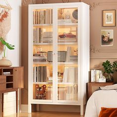 a white bookcase with many books in it's glass doors on the wall