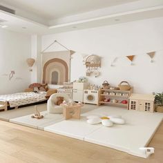 a child's room with white walls and wooden floors, toys on the floor