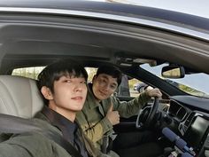 two young men sitting in the driver's seat of a car