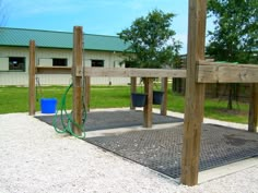 an empty playground in the middle of a grassy area with two buckets and a hose attached to it