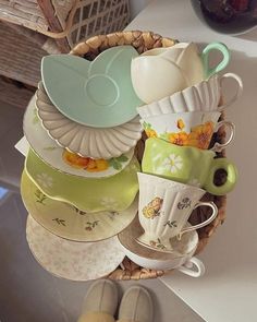 a basket filled with cups and saucers on top of a counter next to a pair of slippers