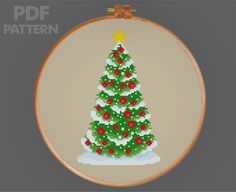 a cross stitch christmas tree with red and green ornaments on it's base is shown